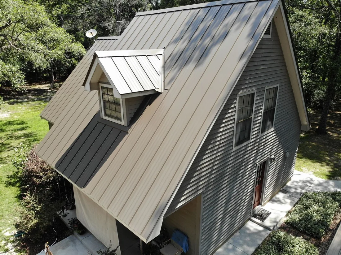 Tan standing-seam metal roof with a metal-clad dormer on a two-story Louisiana home